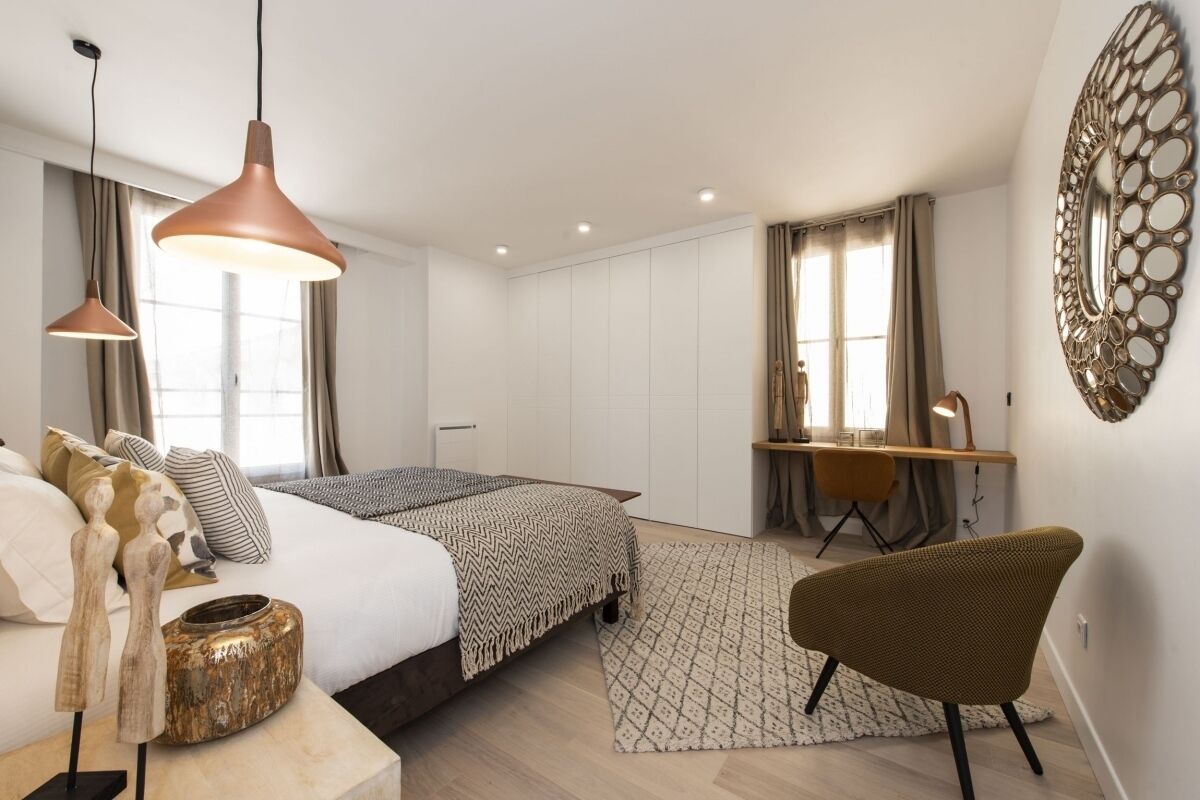 A modern bedroom with a bed, bedside tables, a desk, and a chair.