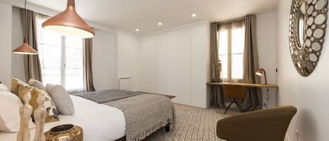 A modern bedroom with a bed, bedside tables, a desk, and a chair.