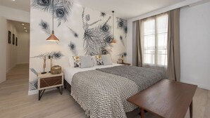 Ein Schlafzimmer mit einem großen Bett, einem Nachttisch aus Holz, einem Tisch und einer Wand mit einem Pfauenfeder-Muster.