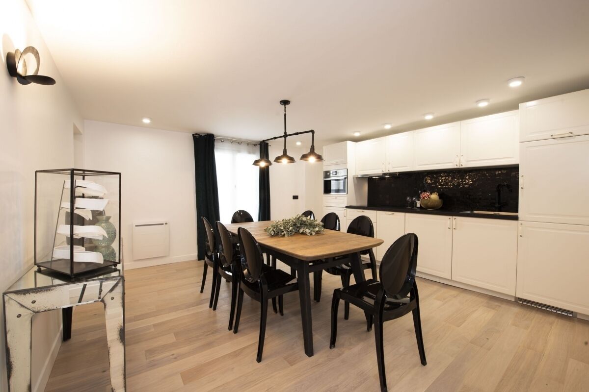 A modern kitchen with white cabinets, a black countertop, and a built-in oven.