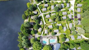 Eine Luftaufnahme eines Wohngebiets mit in einem Raster angeordneten Häusern, einem Schwimmbad und einem Gewässer links.