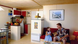 Ein kompakter Wohnraum mit Küchenzeile, Essbereich und einer Sitzecke mit rotem Sofa und Tisch.