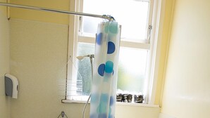 Een badkamer met toilet, bad en douchegordijn.