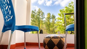 Une pièce avec une chaise bleue, une table bleue et un coussin à motifs sur un sol rouge.