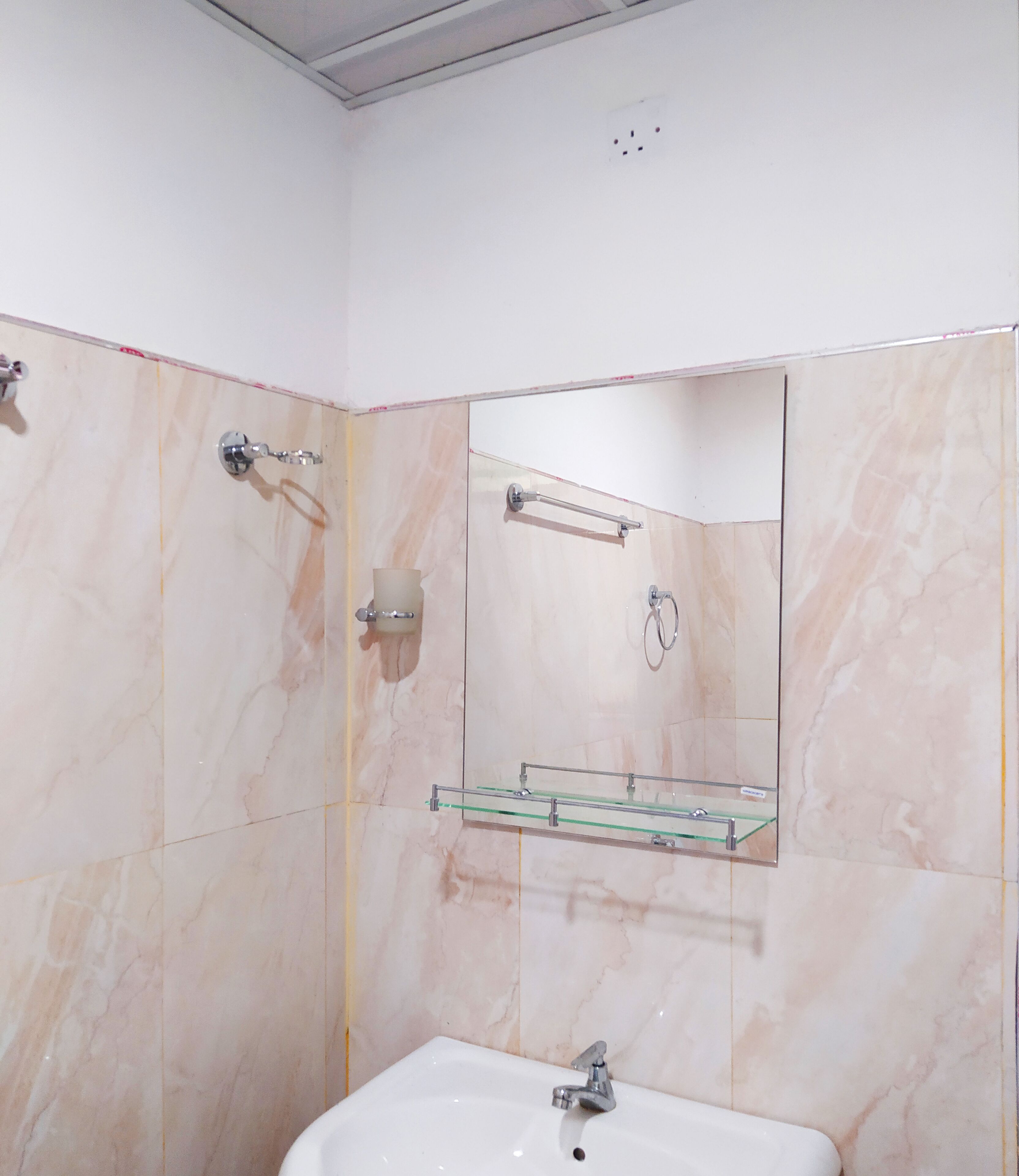 Un baño con lavamanos, espejo, toallero y zona de ducha.