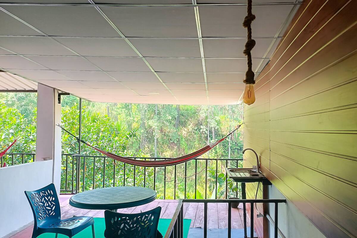 A balcony with a hammock, a round table, and chairs.