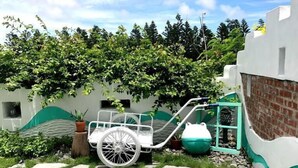 Un espacio exterior accesible en silla de ruedas con un sendero pavimentado, una silla de ruedas blanca y una jardinera verde.