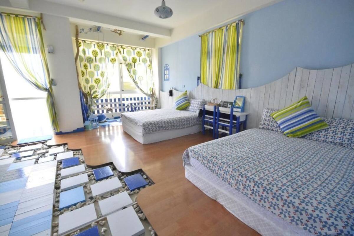 Quarto com duas camas, chão de madeira e vista para o exterior.