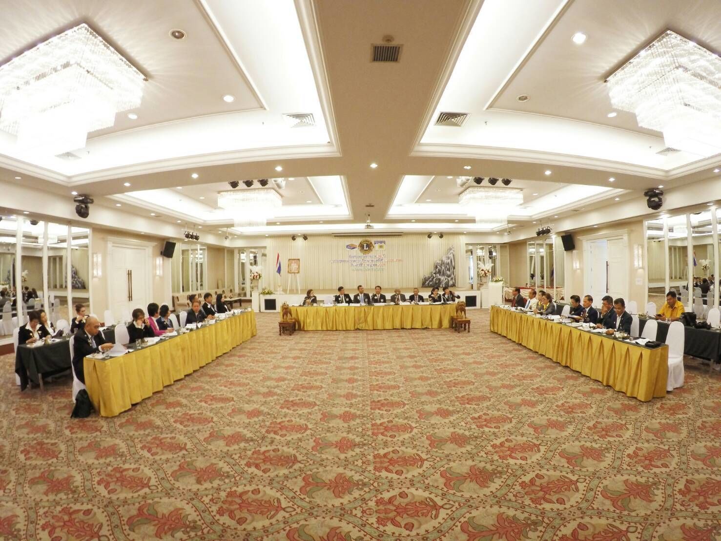 A formal meeting room with a long table, chairs, and a patterned carpet.