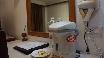 A clean kitchen area with a coffee maker, a hairdryer, and a water bottle on the counter.