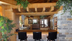A rustic kitchen with a wooden island, stone walls, and hanging plants.