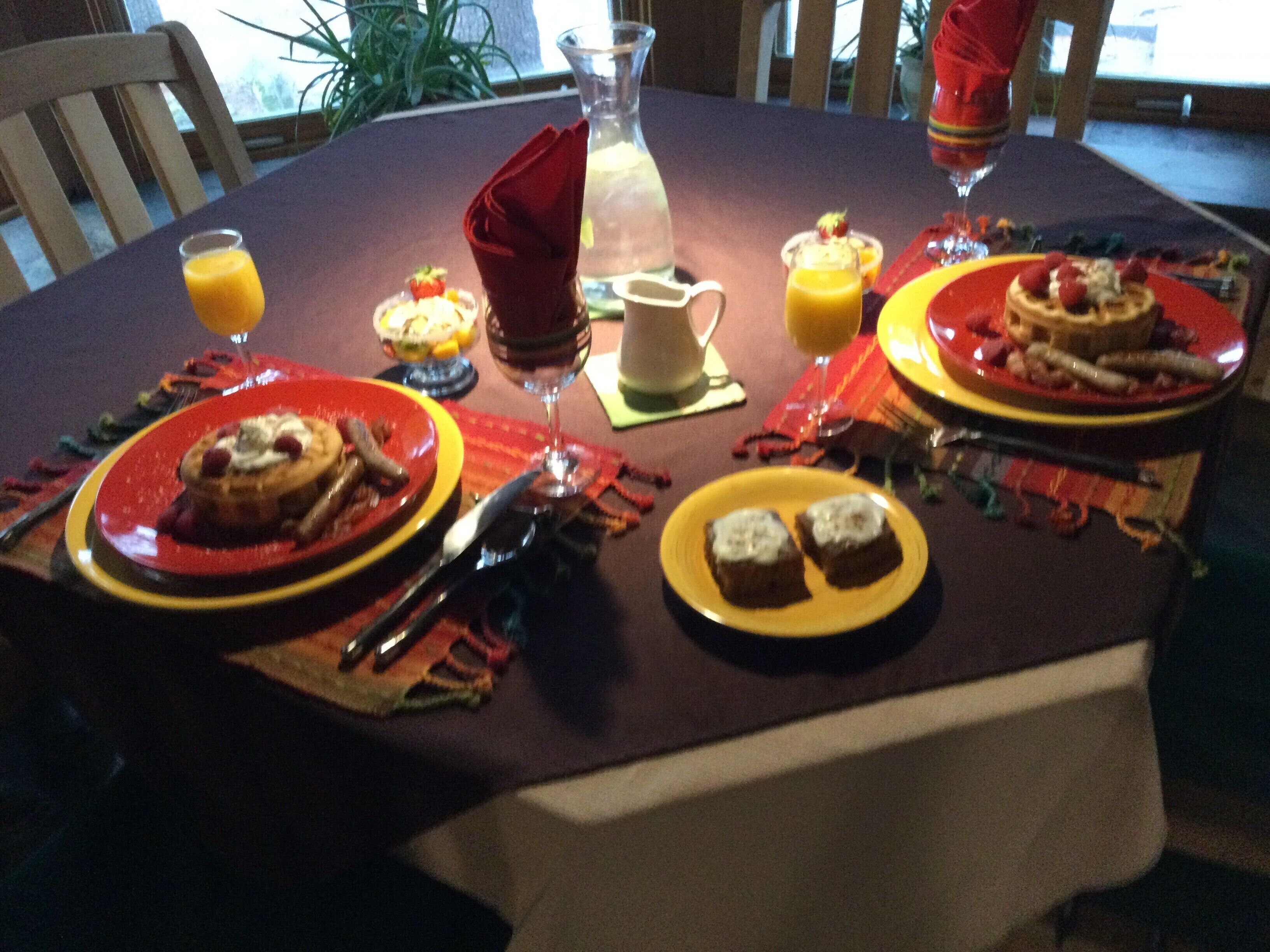 Una mesa de comedor dispuesta con platos de comida, vasos y cubiertos.