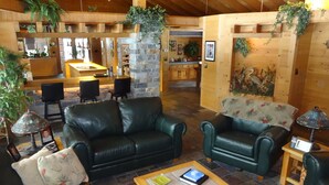 A spacious living area with leather sofas, a coffee table, and a stone accent wall.