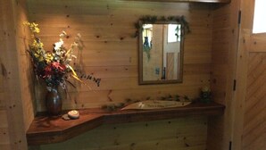 A wooden cabin interior with a wooden countertop, a sink, and a mirror.