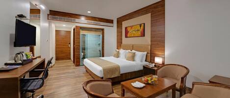A hotel room with a bed, desk, chairs, and a TV.