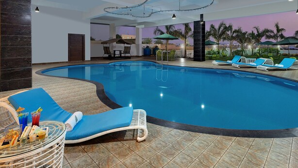 An indoor swimming pool with lounge chairs and a table with drinks.