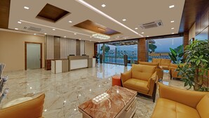 A modern lobby with a reception desk, seating area, and large windows offering a view of the outdoors.
