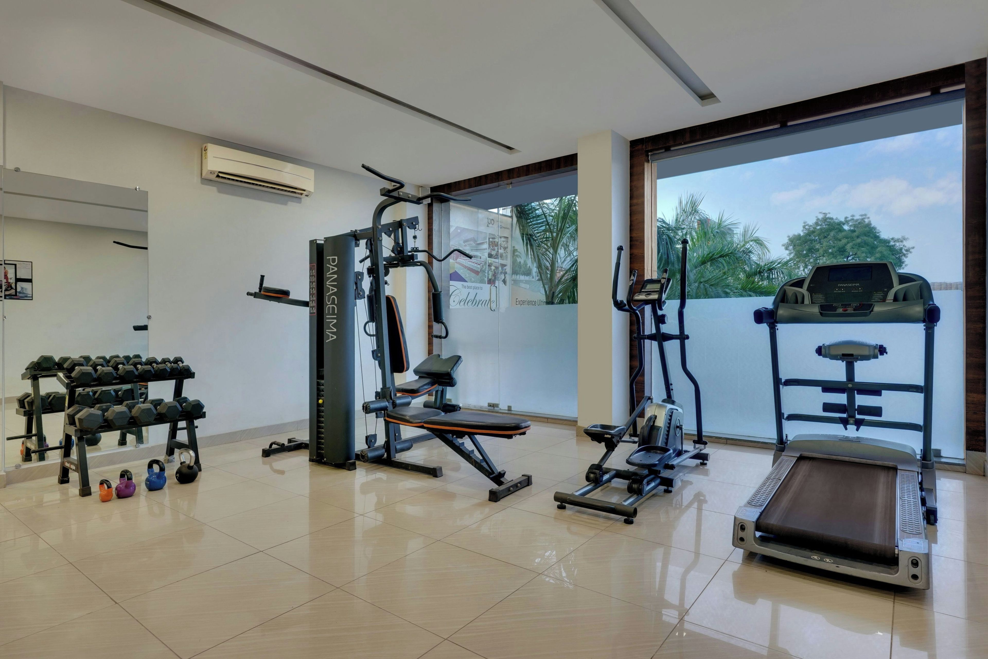 A gym with a treadmill, weight machines, and dumbbells.