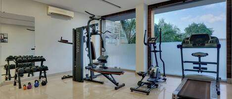 A gym with a treadmill, weight machines, and dumbbells.