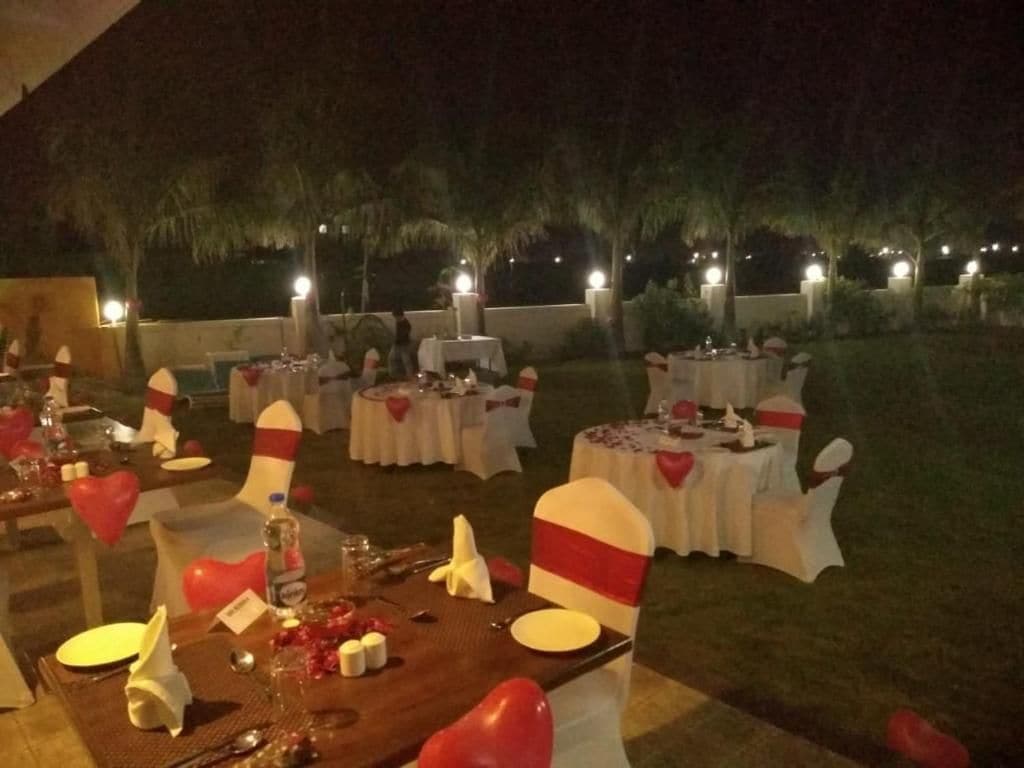 An outdoor dining area with round tables, white tablecloths, and red heart-shaped decorations.