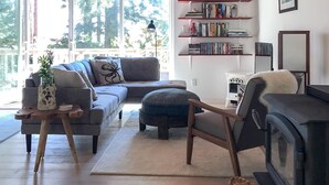 A cozy living room with a wooden ceiling, a sofa, a fireplace, and a bookshelf.