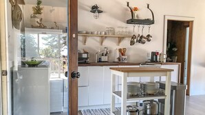 A kitchen with white cabinets, a wooden countertop, a hanging pot rack, and a cart with stacked dishes.