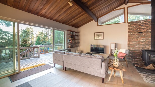 A modern living room with a large sofa, a television, a fireplace, and a bookshelf.