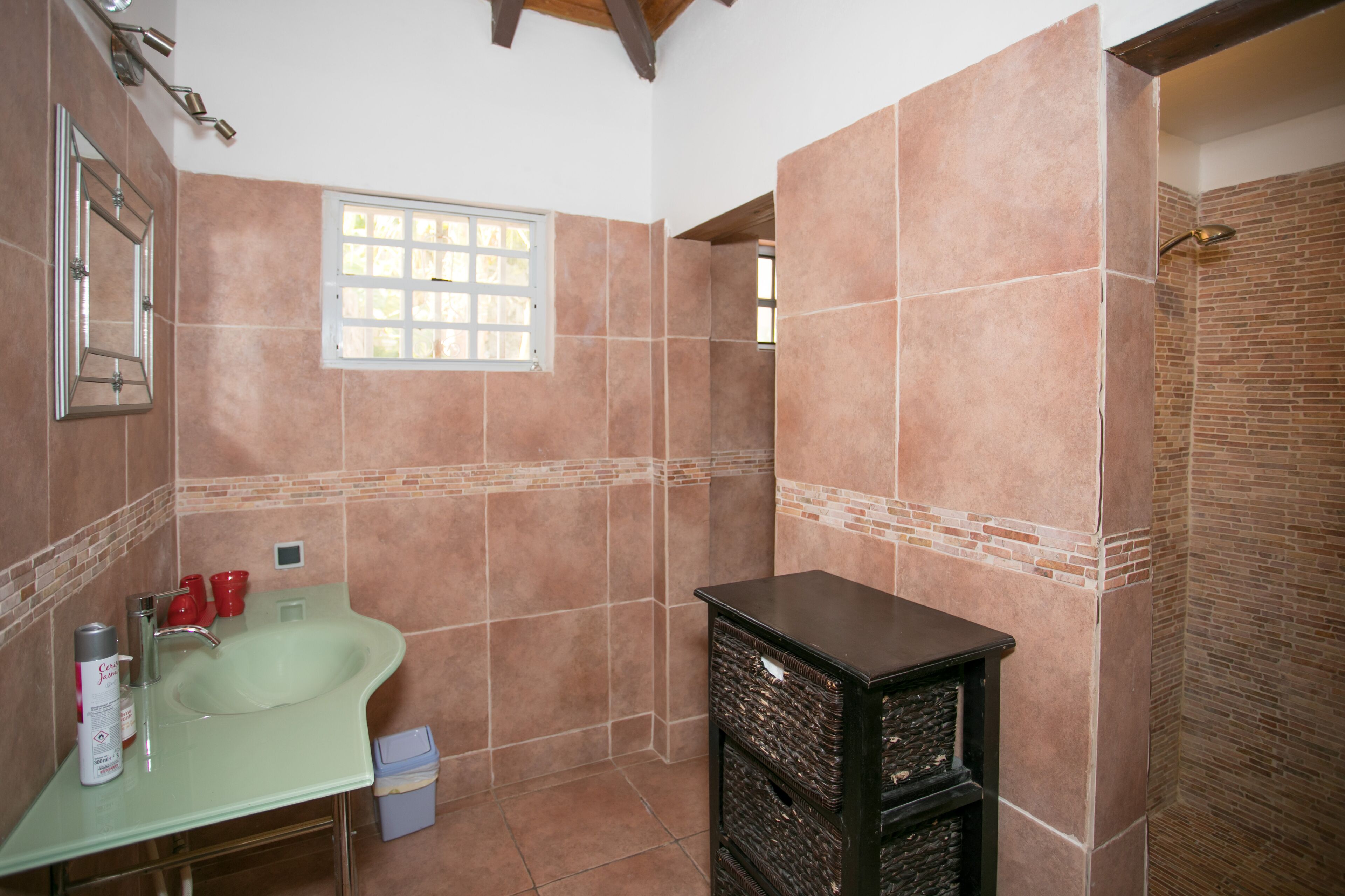 Un baño con lavamanos, espejo y ventana.