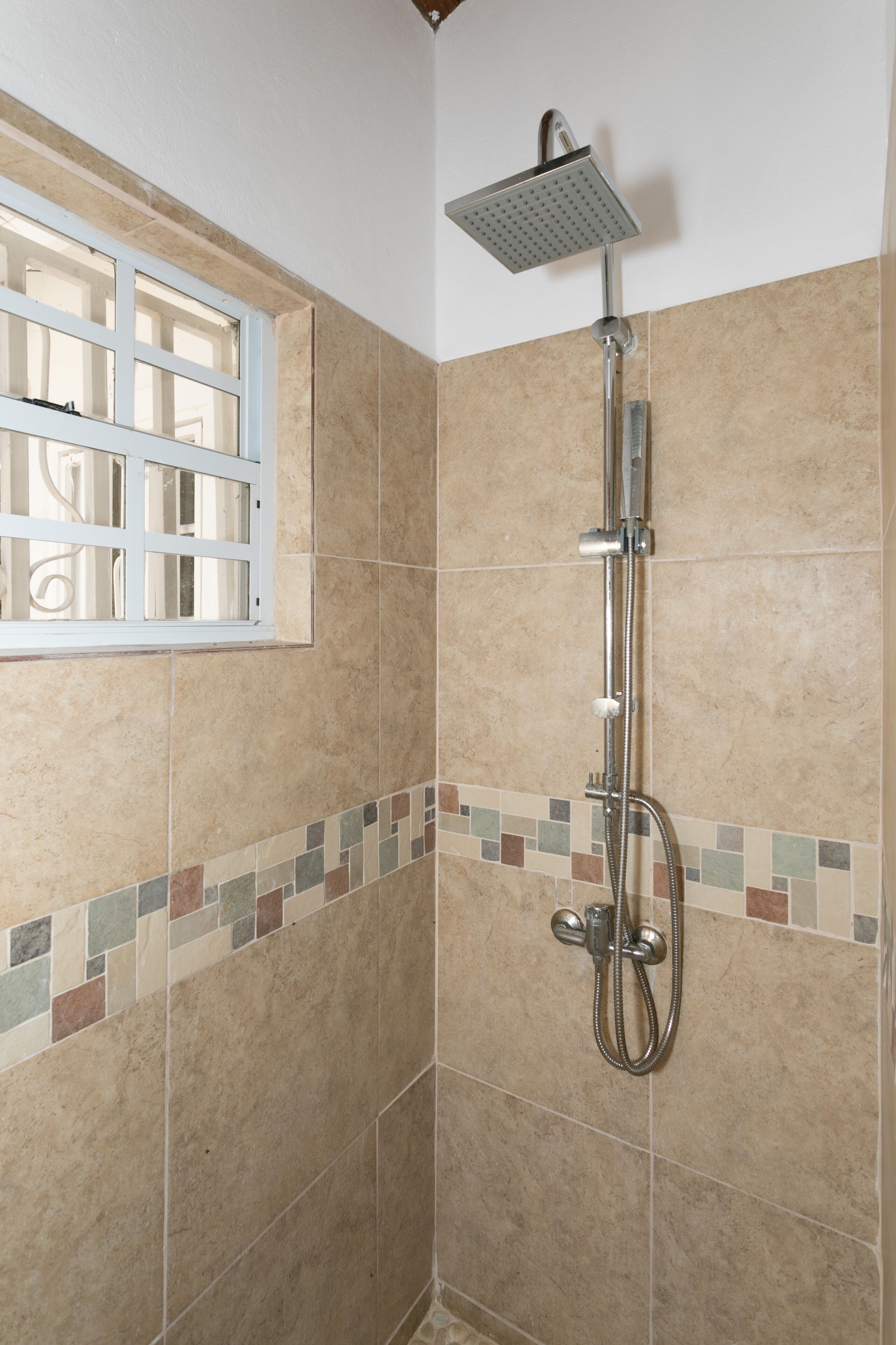 Eine Dusche mit Duschkopf, Handbrause und verstellbarer Armatur.