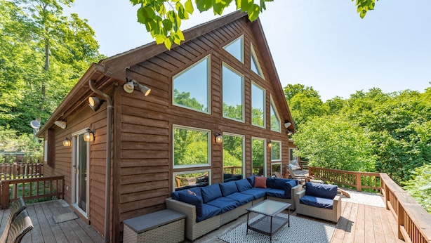 Eine Holzhütte mit einer Terrasse, großen Fenstern und Sitzgelegenheiten im Freien.