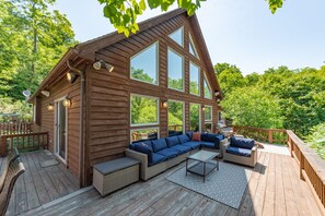 Una cabaña de madera con terraza, ventanas amplias y mobiliario para exteriores.
