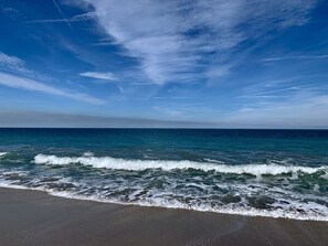 Una playa con olas rompiendo en la orilla bajo un cielo despejado.