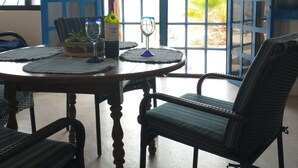 Un comedor con una mesa redonda, sillas, una botella de vino y una copa.