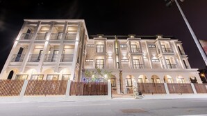 A multi-story hotel with balconies, a gated entrance, and a well-lit facade. - Kiwi Villa (Magong)