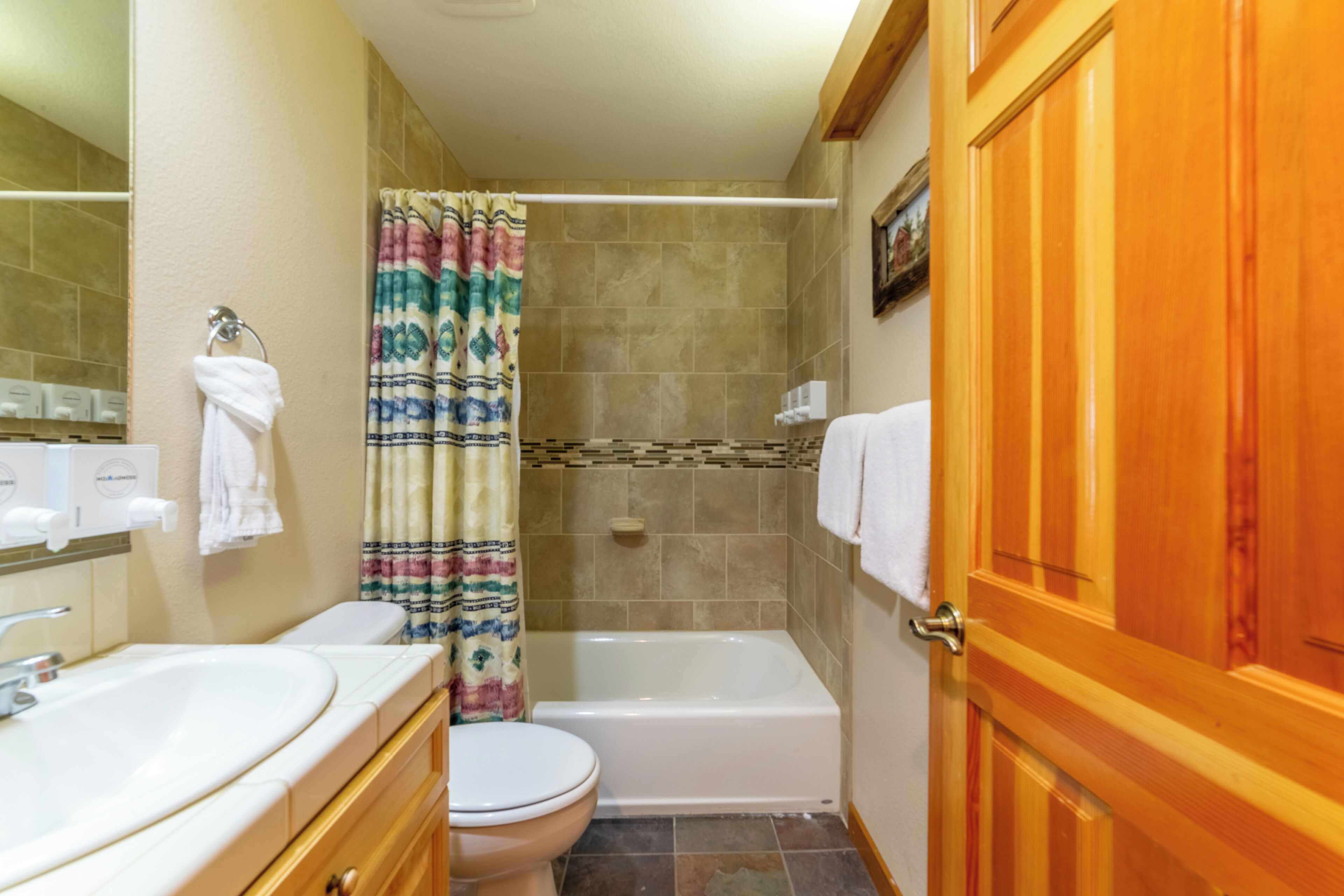 A bathroom with a sink, toilet, bathtub, and shower curtain.