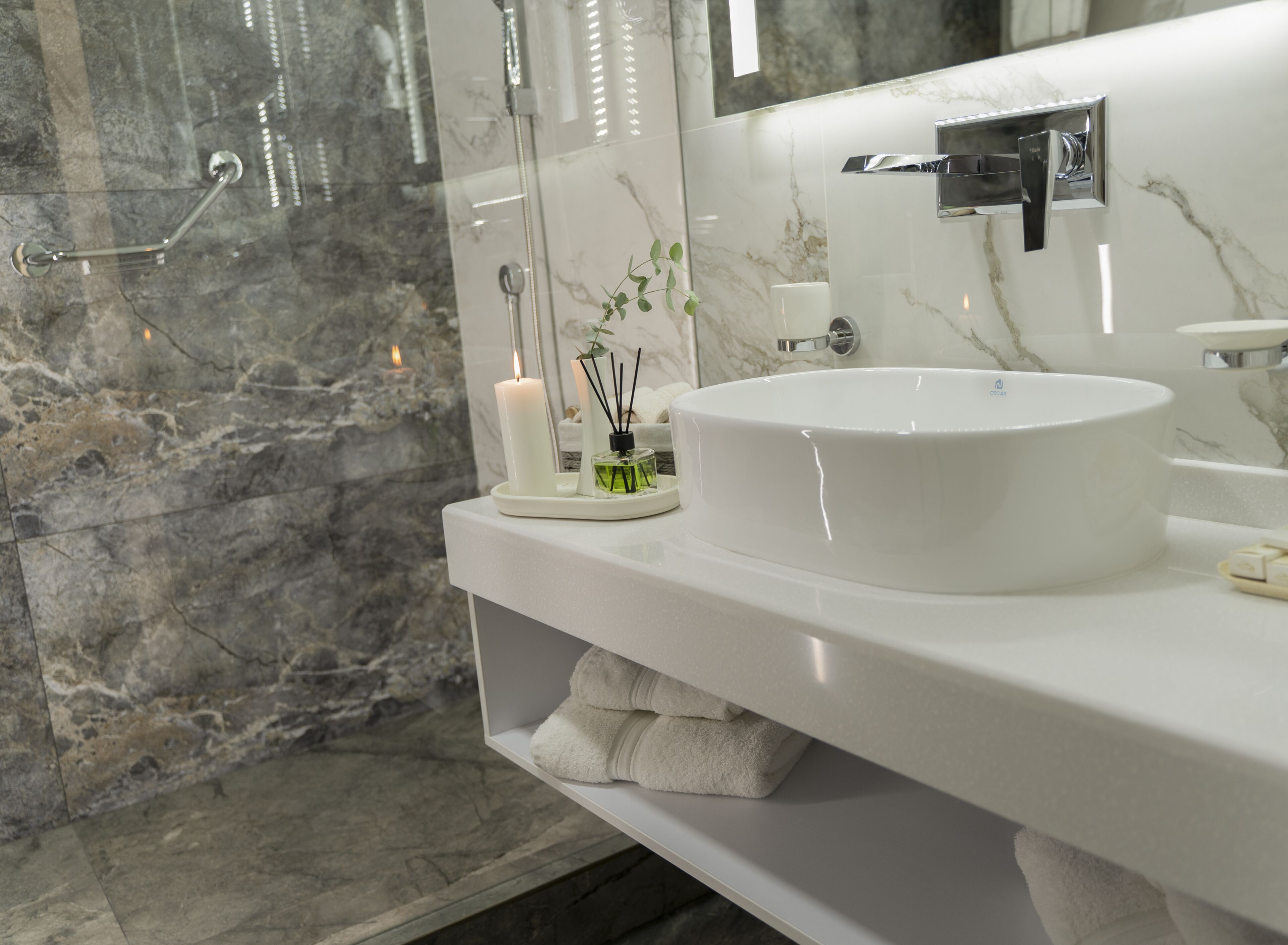 A bathroom with a white sink, a mirror, a towel rack, and a glass shower enclosure.
