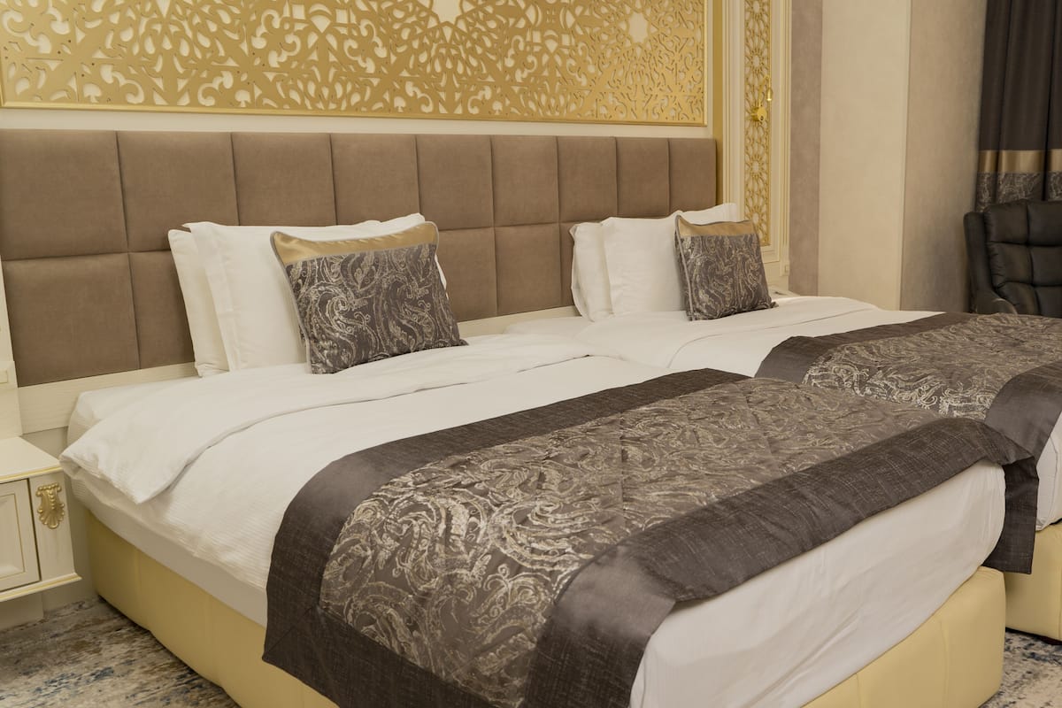 A double bed with a headboard, two bedside tables, and a decorative wall panel.