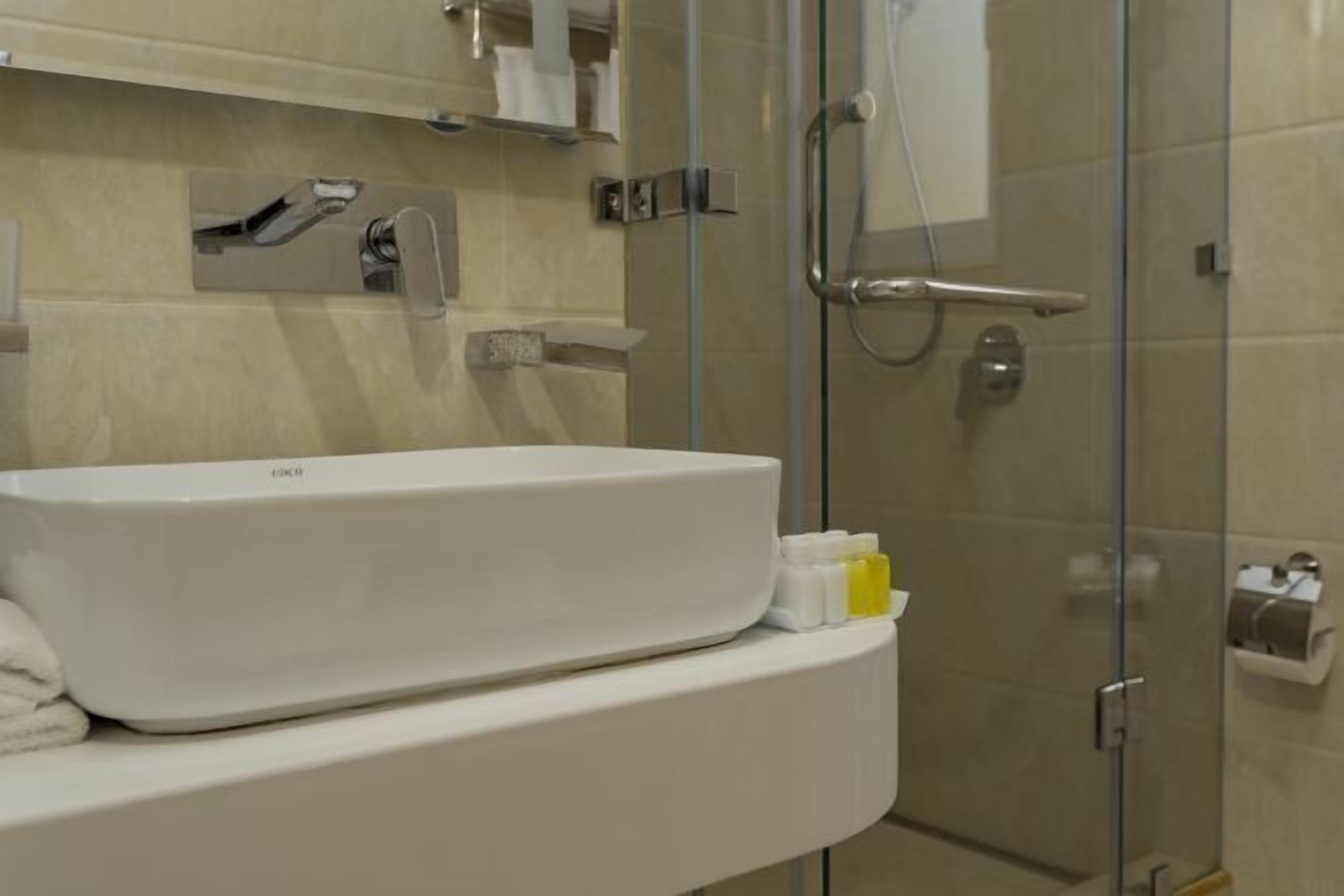 A bathroom with a white sink, a glass shower enclosure, and a towel rack.