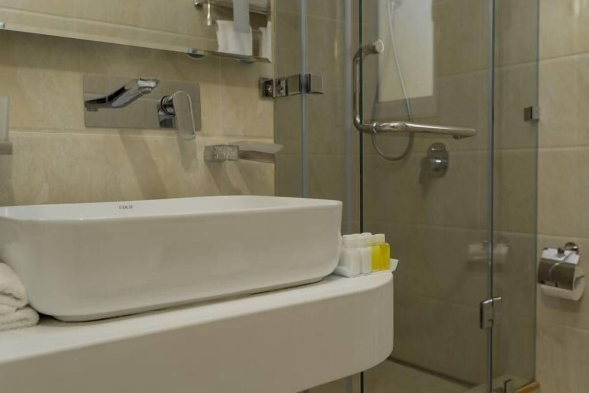 A bathroom with a white sink, a glass shower enclosure, and a towel rack.