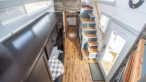 Una cocina compacta con suelo de madera, electrodomésticos integrados y una pequeña zona de estar.