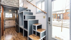 Cocina compacta con refrigerador integrado, piso de madera y ventana con vista al exterior.