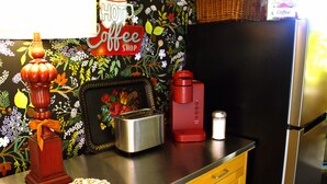 A kitchen counter with a toaster, a red coffee maker, a decorative candle holder, and a framed picture.