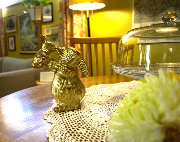 Una mesa con una figurita dorada, un recipiente de vidrio y un mantel de encaje.