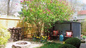 A backyard with a wooden deck, a shed, and a fire pit.