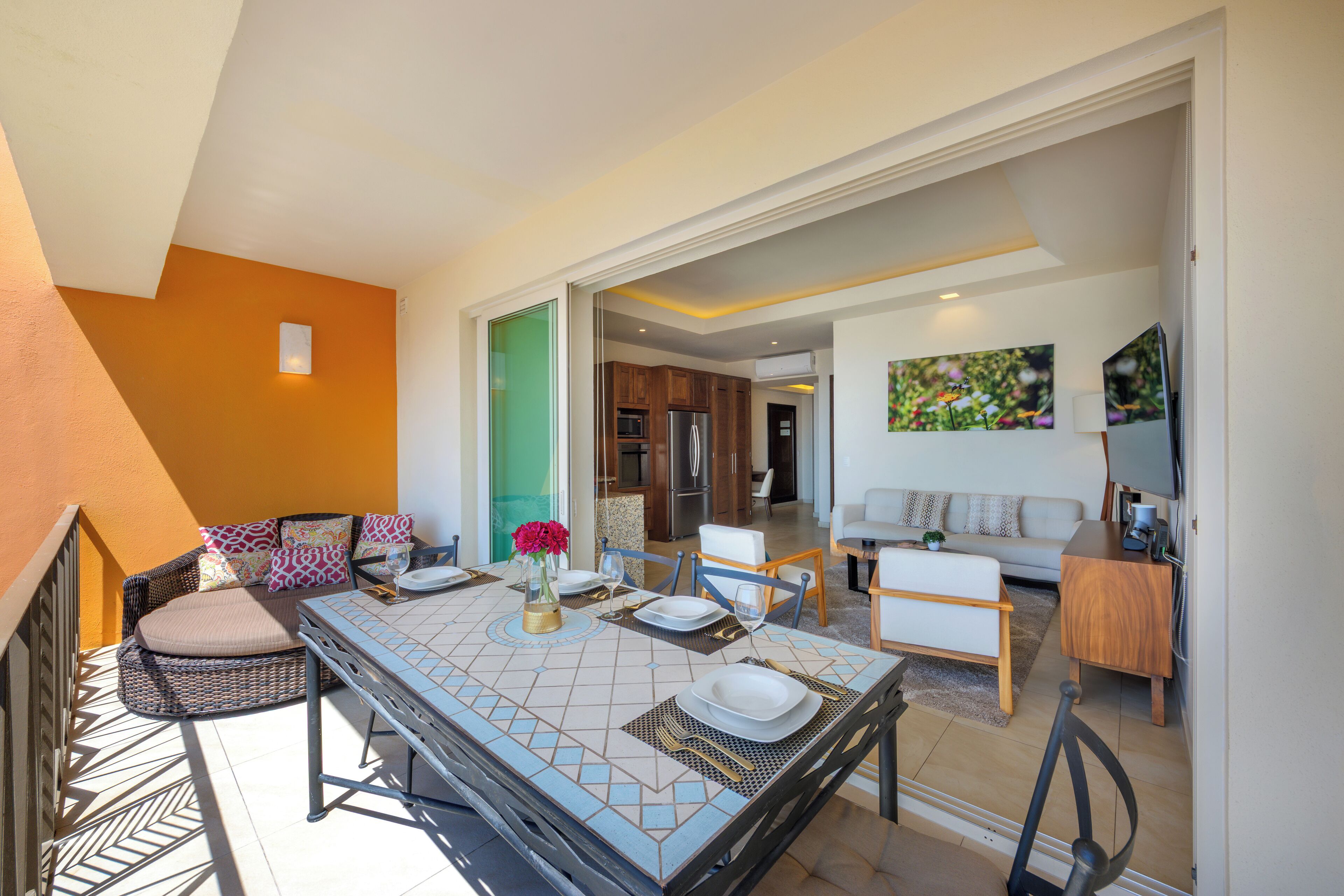 A dining area with a table set for four, a wicker sofa, and a view into the kitchen.