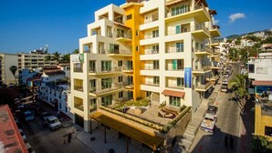 Un hotel de varios pisos con balcones, un patio central y vistas del área urbana circundante.