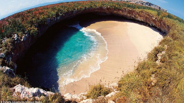 Un arco de roca natural sobre una playa con agua turquesa cristalina.