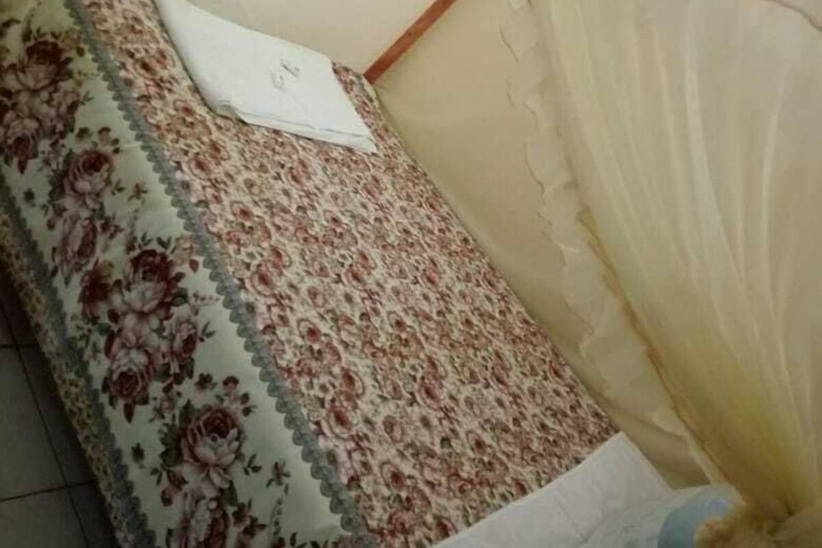 A single bed with a floral bedspread and a mosquito net.