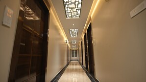 Un largo y estrecho pasillo con piso reflectante, que conduce a una puerta al final.
