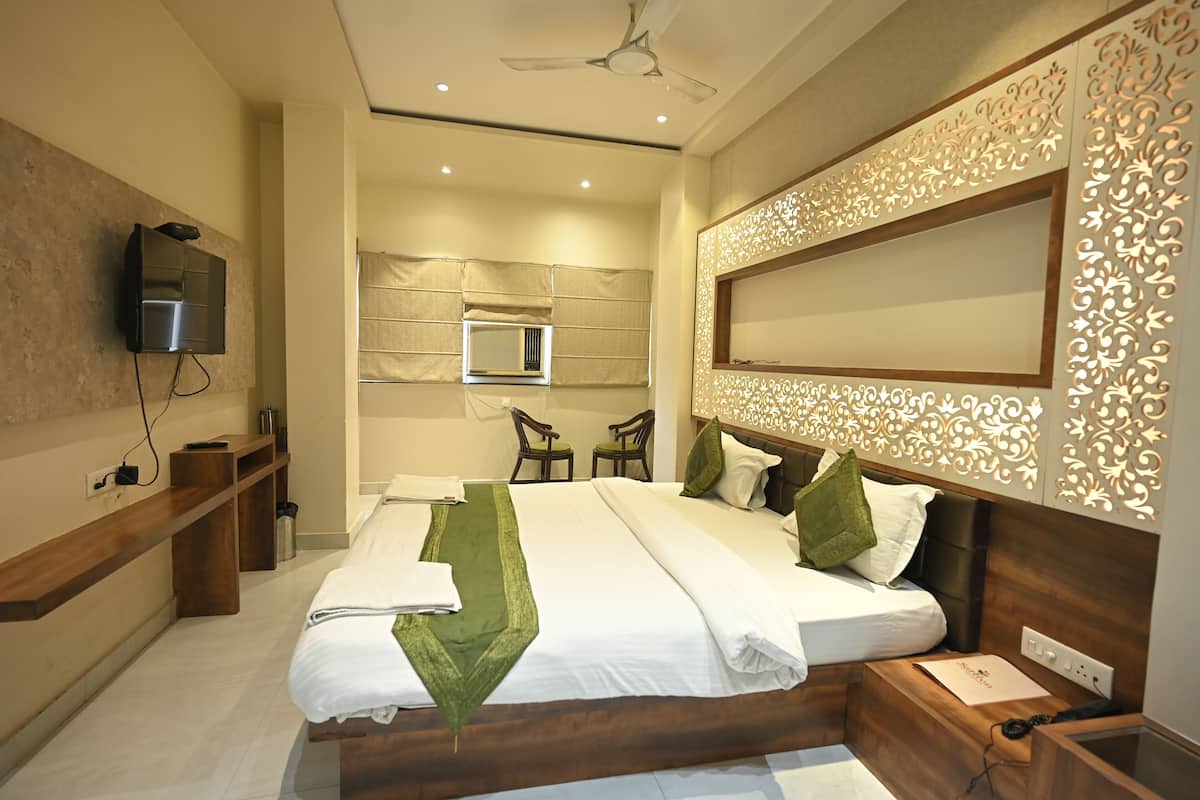 Een moderne hotelkamer met een groot bed, een aan de muur bevestigde televisie en een plafondventilator.